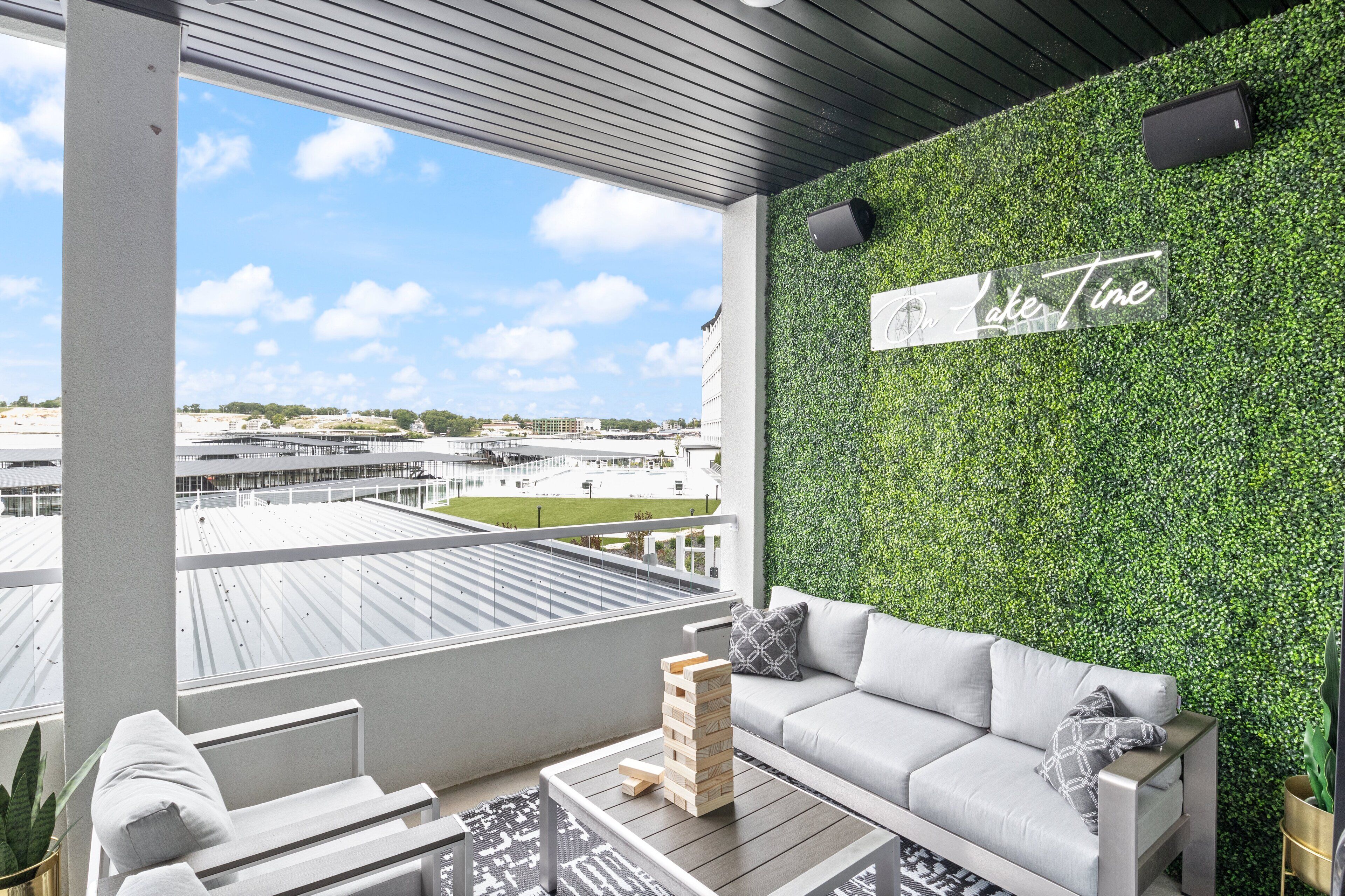 Un balcón moderno con pared verde, sofá y vista al paisaje urbano.