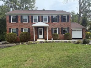 A two-story brick house with a front porch, a garage, and a well-maintained lawn. - 4BR Home with TVs, 2.5 bath, 6 bed, pool, Game-room, Gym-room in Bowie MD (Bowie)