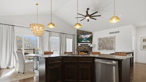 A modern kitchen with a central island, dark wood cabinets, stainless steel appliances, and pendant lighting. - Fairway Retreat (Camdenton)