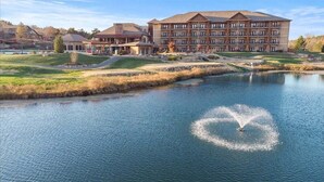A hotel with a large building, a pond, and a fountain. - Fairway Retreat (Camdenton)