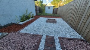 Un patio empedrado con un sendero de grava y bordes de ladrillo.