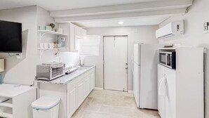 Cocina compacta con armarios blancos, un microondas integrado y una pequeña encimera.