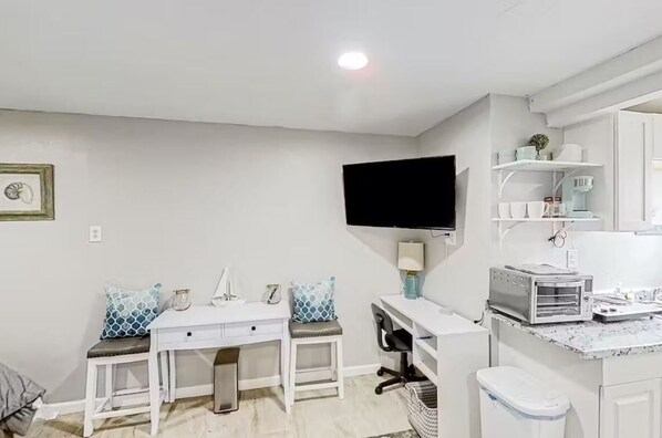 A compact living space with a kitchenette, a dining area, and a TV mounted on the wall. - Cozy Guesthouse Fire Pit near Busch Gardens & USF (Tampa)
