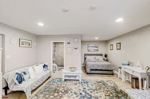 Une chambre à coucher moderne et bien éclairée, comprenant un lit, un canapé, un bureau et une petite table.