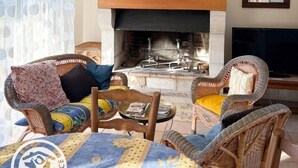 Ein Wohnzimmer mit Rattanmöbeln, einem Kamin und einem Fernseher.