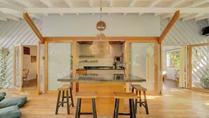 Una cocina moderna con una isla central, taburetes de bar y una lámpara colgante.