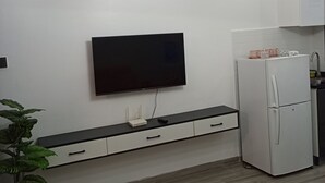 Una cocina moderna con televisión integrada, un refrigerador blanco y una planta en maceta.