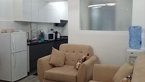 Una sala de estar moderna con un sofá color beige, una mesita redonda y una cocina al fondo.