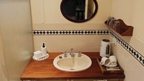Un baño con un mueble de tocador de madera, un espejo redondo, un lavabo y un perchero para toallas.