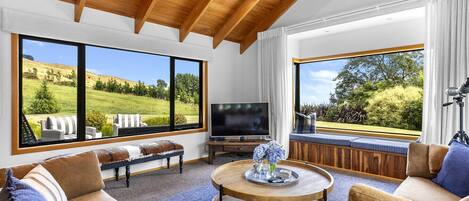 A spacious living room with large windows, a wooden ceiling, and a comfortable seating area.