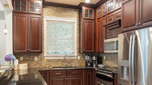 Una cocina moderna con armarios de madera oscura, electrodomésticos de acero inoxidable y un tapete estampado.