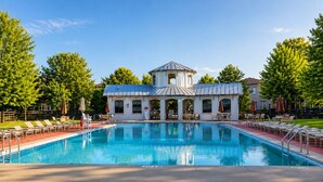 Una piscina con sillas de descanso y un edificio con una torre al fondo.