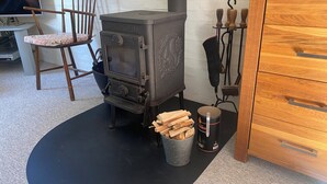 A wood-burning stove, a chair, a bucket with firewood, and a wooden cabinet. - Holiday house – located in a forest area (Glesborg)
