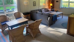 A living room with a sofa, chairs, a table, and a lamp. - Holiday house – located in a forest area (Glesborg)
