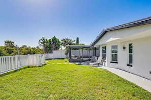 A modern house with a covered patio, a fenced backyard, and a well-maintained lawn.
