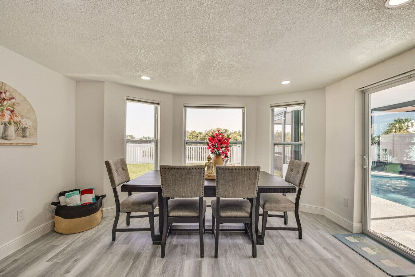 A dining area with a table and chairs, large windows, and a view of a swimming pool.