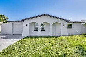 A single-story house with a white exterior, a garage, and a well-maintained lawn.