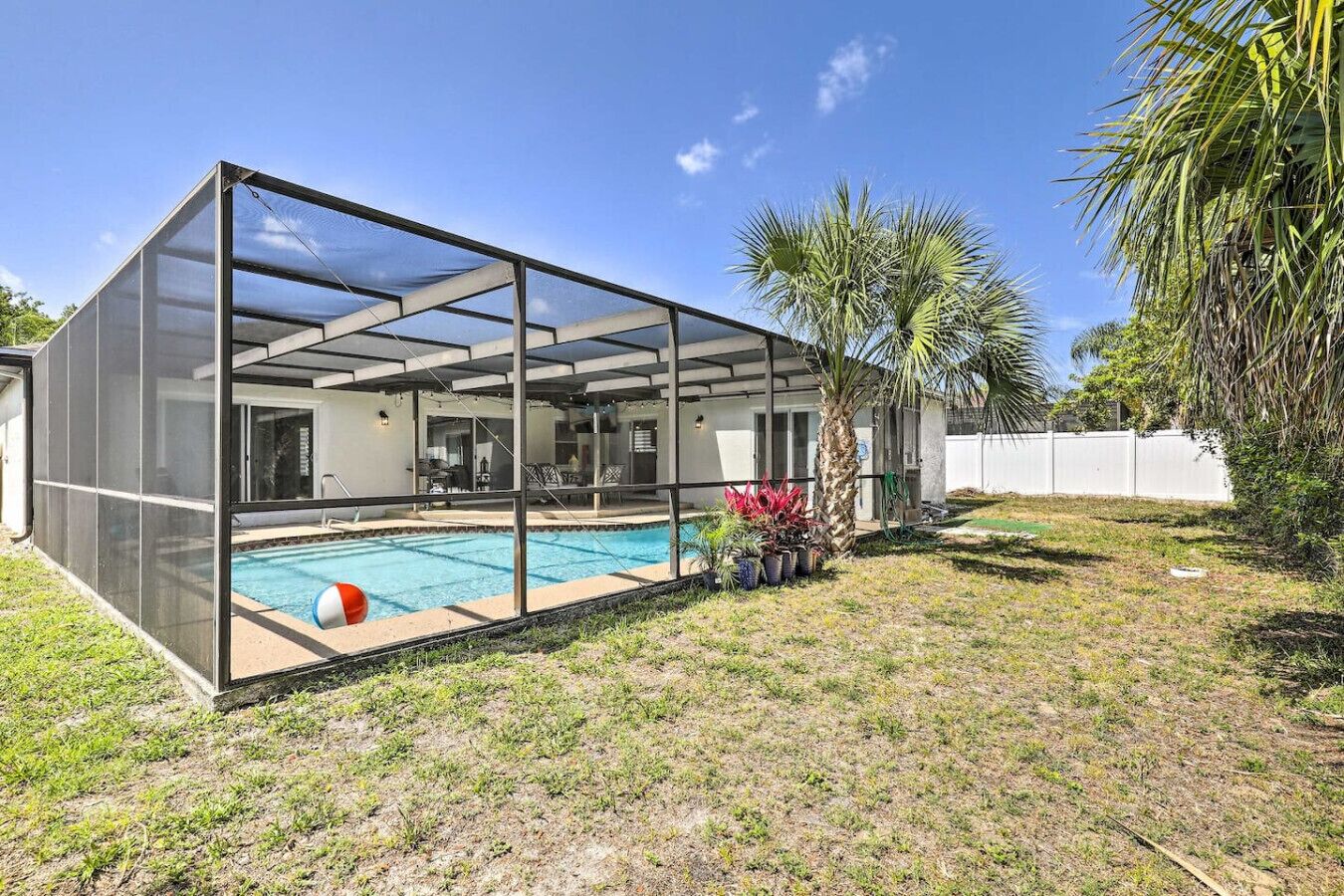 Et moderne hus med en swimmingpool under glas, en terrasse og en indhegnet have.