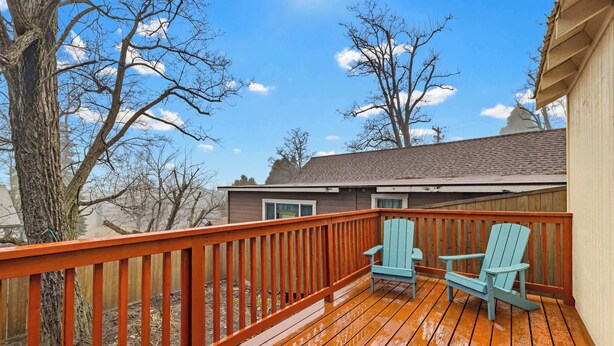 A wooden deck with two blue Adirondack chairs, a house in the background, and leafless trees. - Immerse in Julian Cozy Cabin w Fireplace & Deck (Julian)