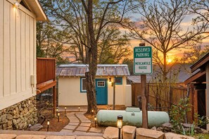 A rustic cabin with a blue door, surrounded by trees and a sunset in the background. - Immerse in Julian Cozy Cabin w Fireplace & Deck (Julian)