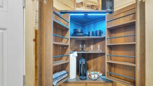 A wooden cabinet with shelves, a coffee maker, and a bottle of hand sanitizer. - Immerse in Julian Cozy Cabin w Fireplace & Deck (Julian)