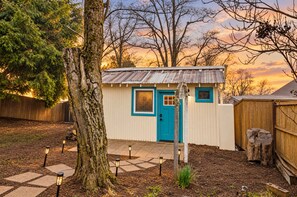 A small shed with a blue door and windows, surrounded by a wooden fence, trees, and a stone pathway. - Immerse in Julian Cozy Cabin w Fireplace & Deck (Julian)