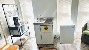 Et kompakt køkken med et køleskab, kaffemaskine og vask.