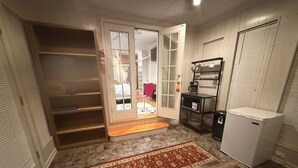 En kompakt opholdsstue med indbygget skab, et lille tekøkken med køleskab, og et tæppe med et mønster på gulvet.