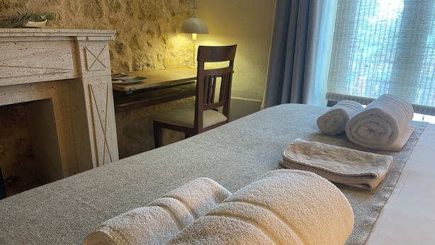 Une chambre d’hôtel avec un grand lit, un bureau et une chaise. Il y a des serviettes sur le lit et une lampe sur le bureau.