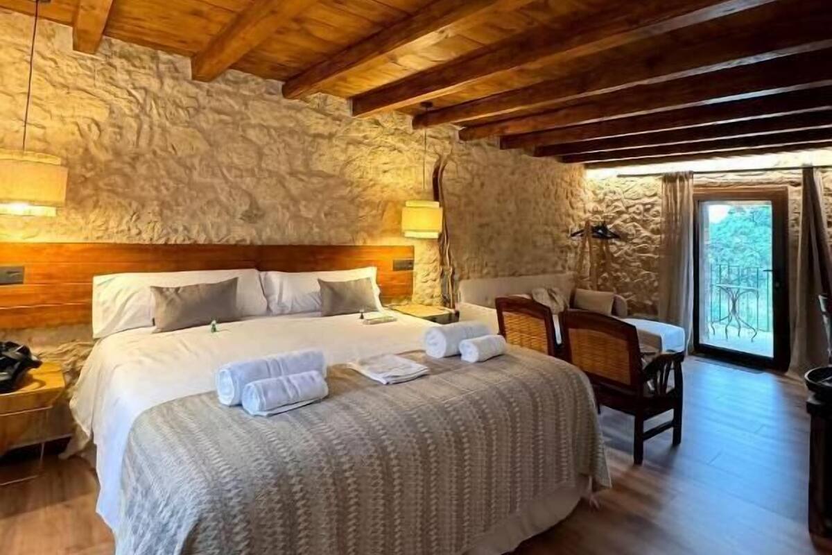 Een gezellige slaapkamer met een houten plafond, een stenen muur en een bed met netjes opgevouwen handdoeken.