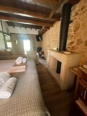 Una habitación acogedora con pared de piedra, chimenea, cama con toallas enrolladas y un banco de madera.