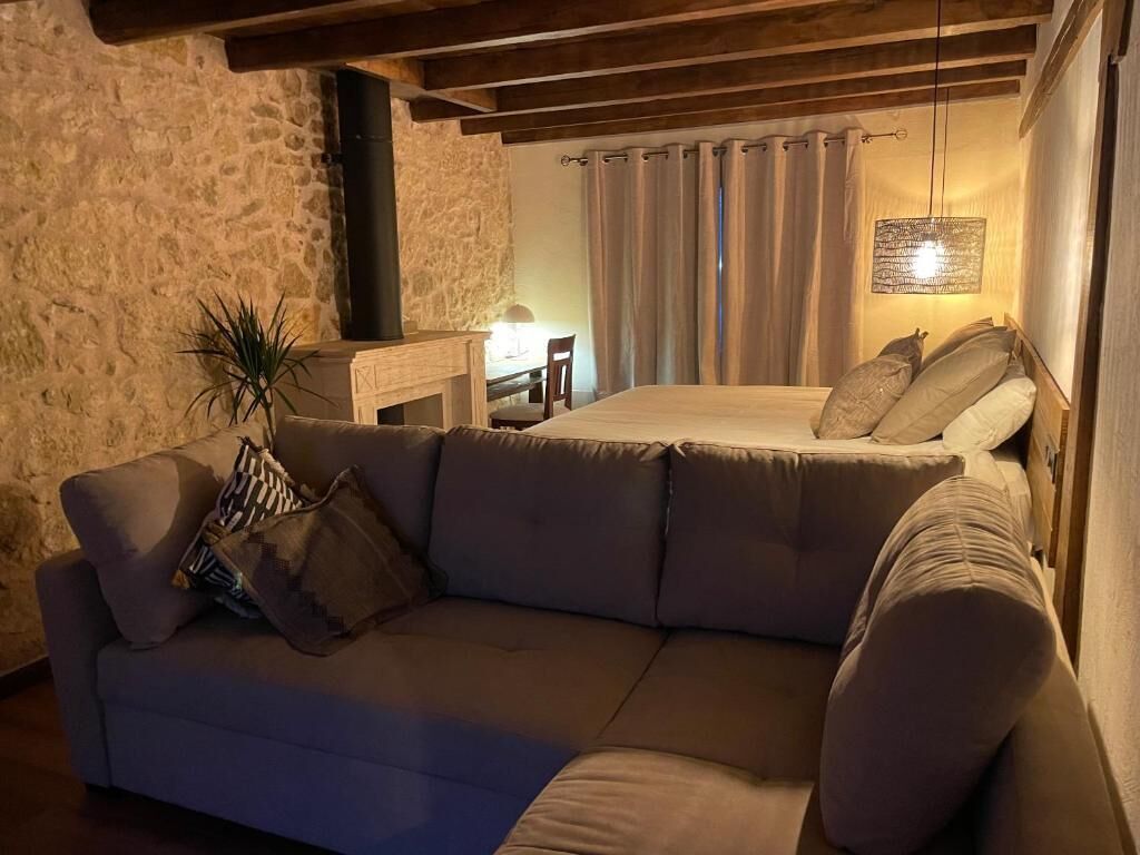 Een knus vertrek met een bank, een bed, een stenen muur en een open haard.