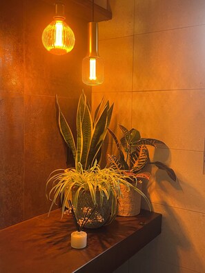 Un baño con tocador de madera, una planta en maceta y un colgador de luz.
