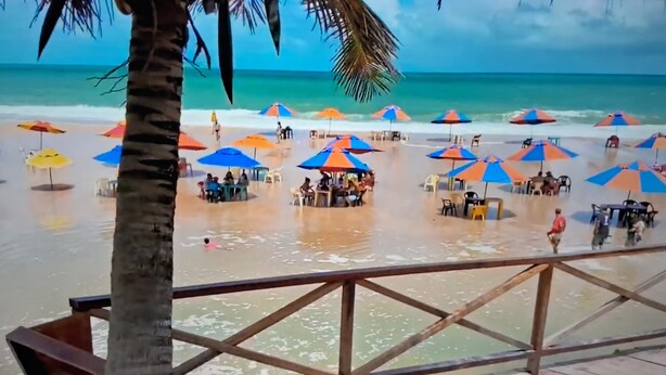 A beach with umbrellas and tables, palm trees, and the ocean. - Apartment for 4 people - Spacious and 700m from the beach. (João Pessoa)