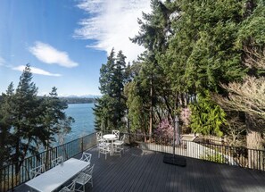 Um terraço com mesa e cadeiras de frente para um lago, cercado por árvores.