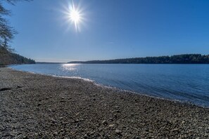 Une plage de galets, avec un ciel dégagé et une eau calme.