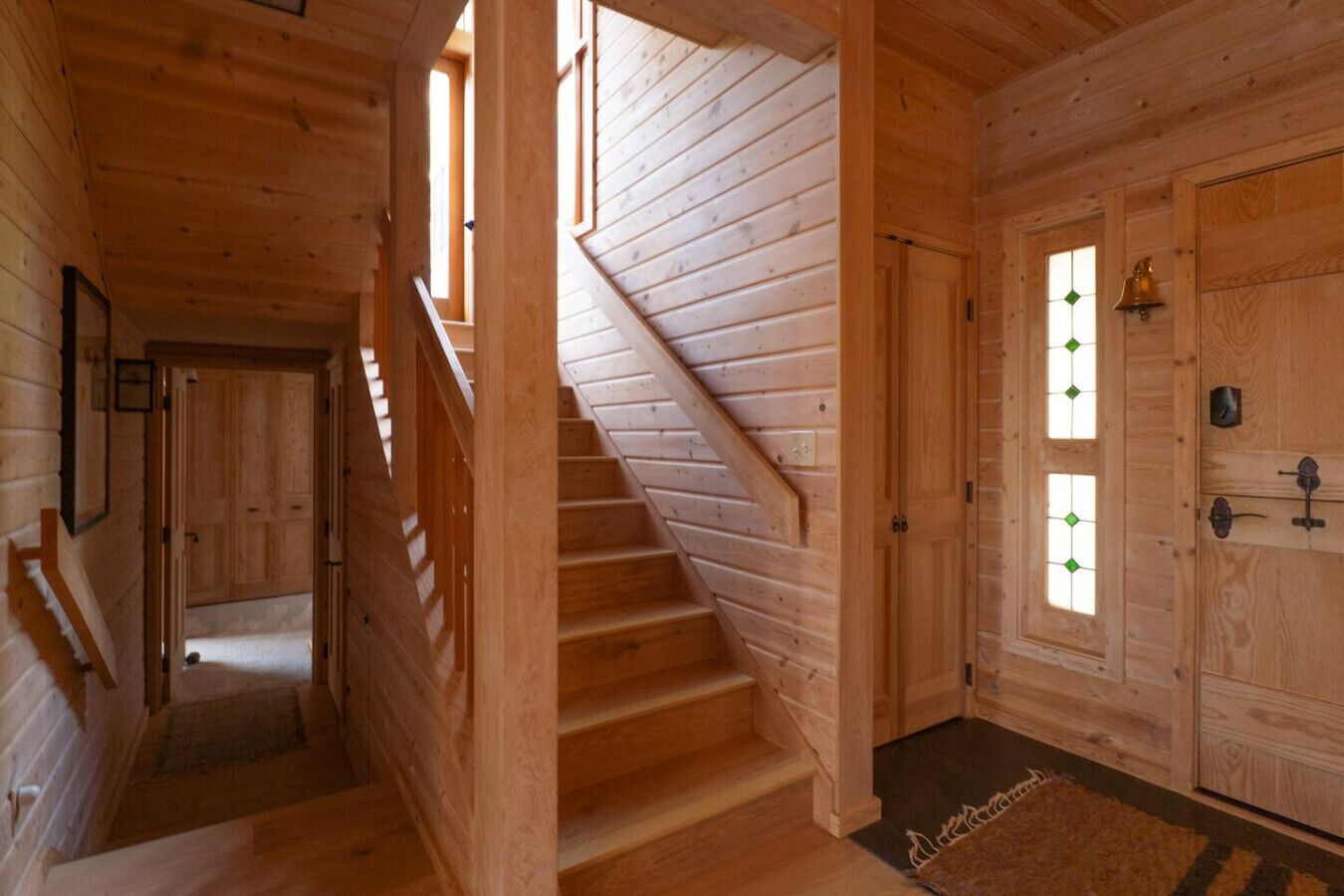 Un escalier en bois menant à une porte dotée d’une fenêtre.