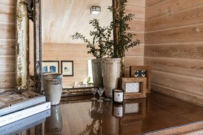 A wooden interior with a polished table displaying books, a vase with greenery, and a small framed picture. - Luxury Bainbridge Escape, Beach, Spa (Bainbridge Island)