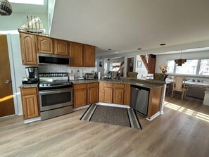 Eine moderne Küche mit Holzschränken, Edelstahlgeräten und einer Granitabdeckung.