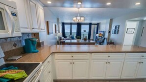 A modern kitchen with white cabinetry, a built-in oven, and a large island with a sink. - Nice NEW 2BR,Direct Oceanfront in Private Arcadian (Myrtle Beach)