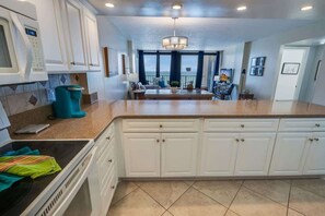 A modern kitchen with white cabinetry, a built-in oven, and a large island with a sink. - Nice NEW 2BR,Direct Oceanfront in Private Arcadian (Myrtle Beach)