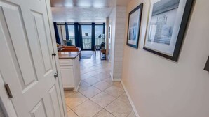 A hallway with a view to a balcony, tiled flooring, and framed pictures on the wall. - Nice NEW 2BR,Direct Oceanfront in Private Arcadian (Myrtle Beach)