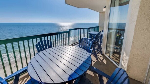 A balcony with a round table and chairs, overlooking a beach and the ocean. - New Private 4BR Ashworth,  Direct Oceanfront Views (North Myrtle Beach)