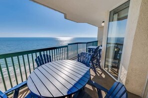 Un balcone con un tavolo rotondo e sedie, vista sulla spiaggia e sull'oceano.