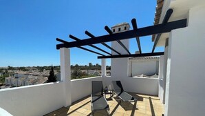 En takterrass med en pergola, ett bord med stolar och utsikt över stadsbilden.