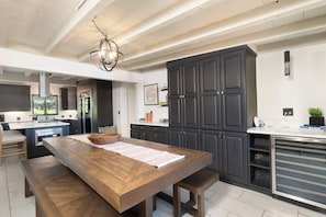 Een moderne keuken met donkere kastjes, een houten eettafel en een hangende lamp.