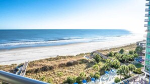 A beachfront hotel with a view of the ocean, a beach, and a parking area with umbrellas. - 12th Floor, Stunning View Contemporary Oceanfront (North Myrtle Beach)