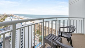 A balcony with a view of the beach and ocean, a pool area, and a sign for a hotel. - 12th Floor, Stunning View Contemporary Oceanfront (North Myrtle Beach)