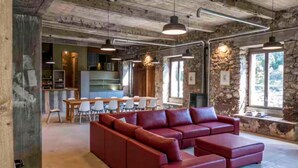 Un espace de vie moderne avec un canapé rouge, un coin repas avec des chaises et une cuisine en arrière-plan.