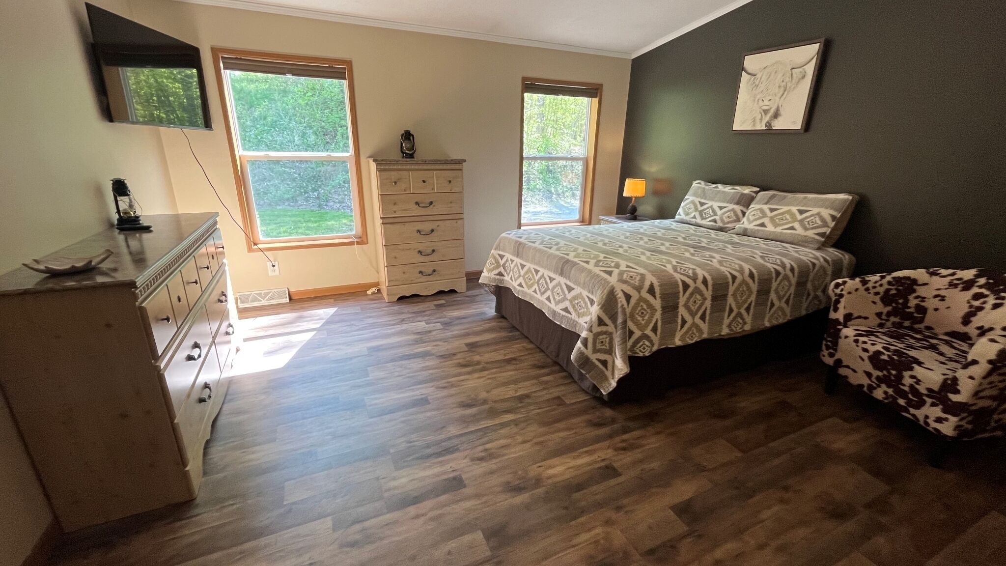 Une chambre à coucher avec un lit, une commode et deux fenêtres.